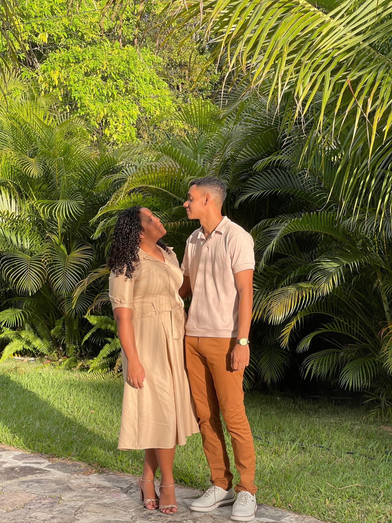 Gustavo e Alícia em meio à vegetação, sorrindo um para o outro